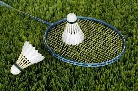Duas pessoas jogando badminton, com raquetes e peteca
