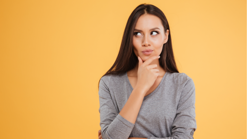 mulher com expressão facial desconfiada olhando para o lado em fundo laranja
