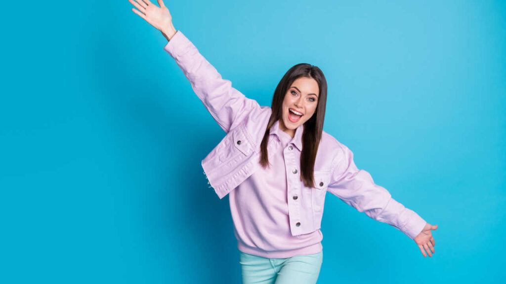 mulher sorrindo com os braços abertos em fundo azul