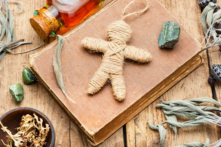 Mesa com itens usados na magia do Vodu, incluindo um boneco.