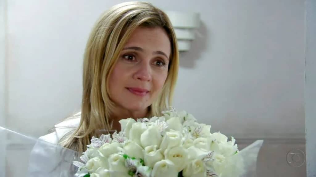 Carminha de cabelo solto, roupa branca, segurando buquê de rosas brancas, em cena de Avenida Brasil