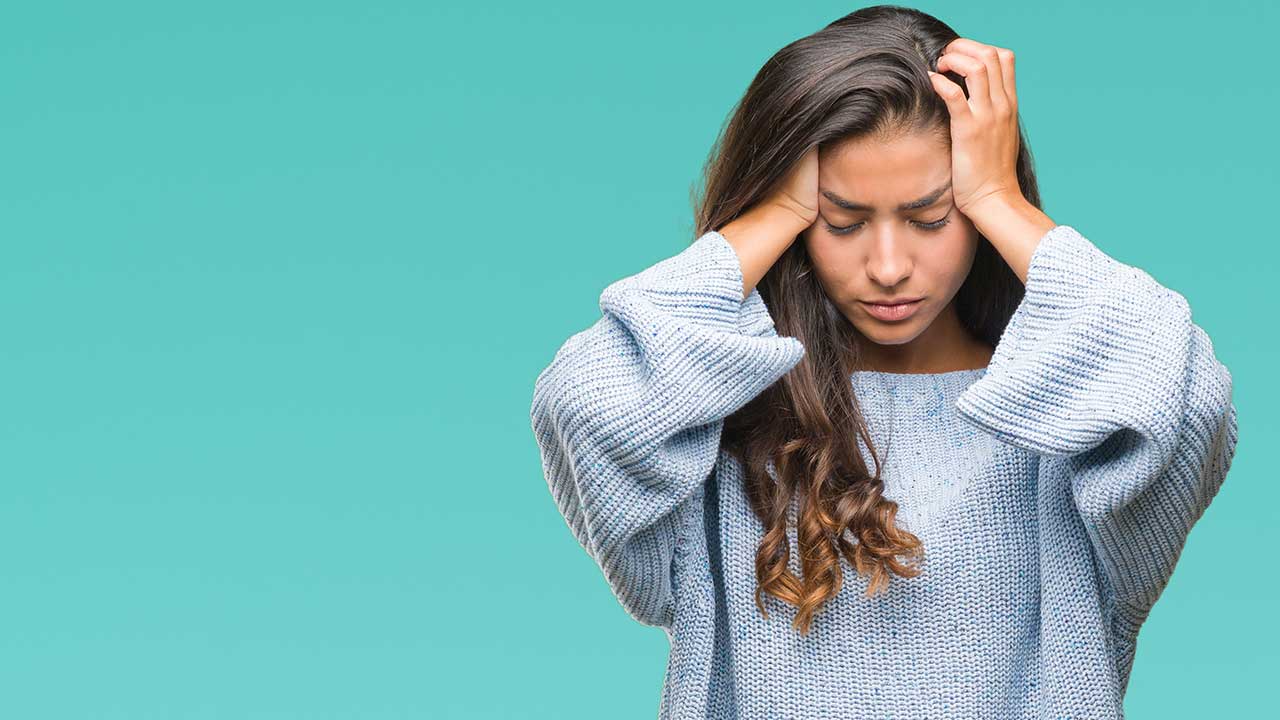 mulher com as mãos na cabeça para baixo em fundo azul