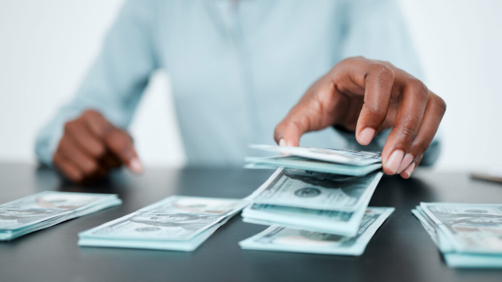 homem separando montes de dinheiro em dólar