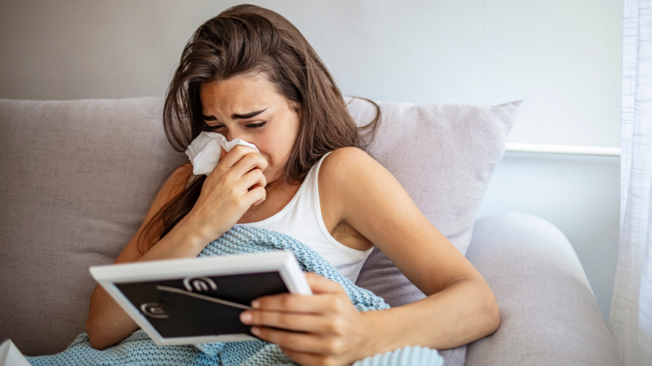 Imagem de uma mulher chorando enquanto olha para um quadro e assoa o nariz em um lenço de papel