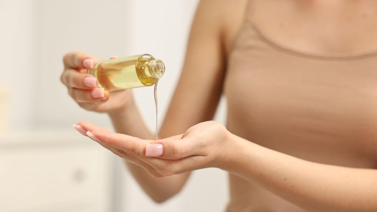 Mulher colocando óleo essencial na mão.