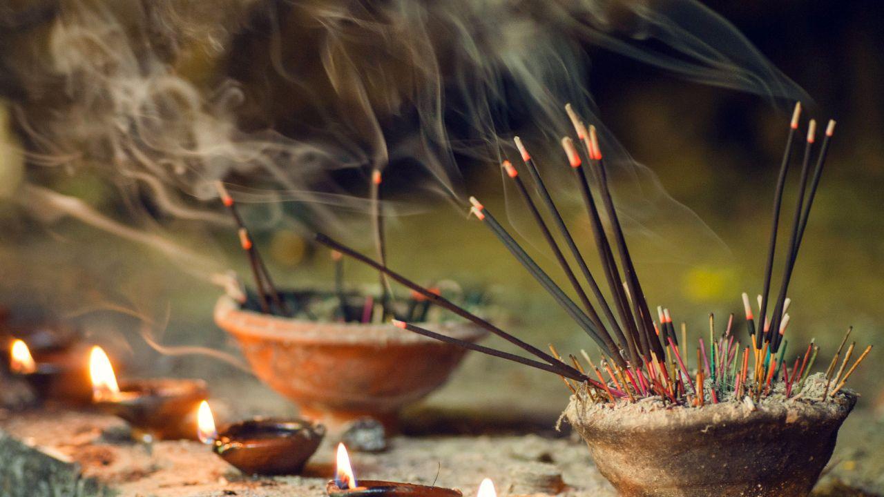 Varetas de incenso dentro de um vaso de barro ao ar livre.