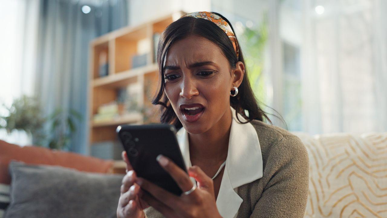 Imagem de uma pessoa com o celular na mão e semblante de indignação