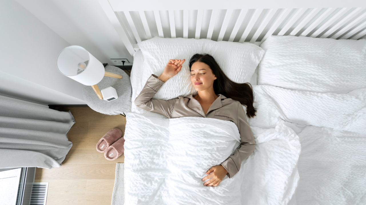 Imagem de uma mulher deitada em uma cama, coberta com um coberto branco